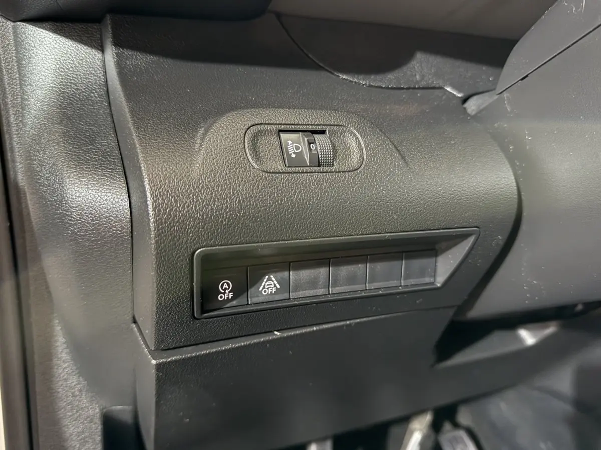 Détail du tableau de bord noir du Peugeot Rifter 2019, montrant les commandes d’éclairage et d’assistance à la conduite.