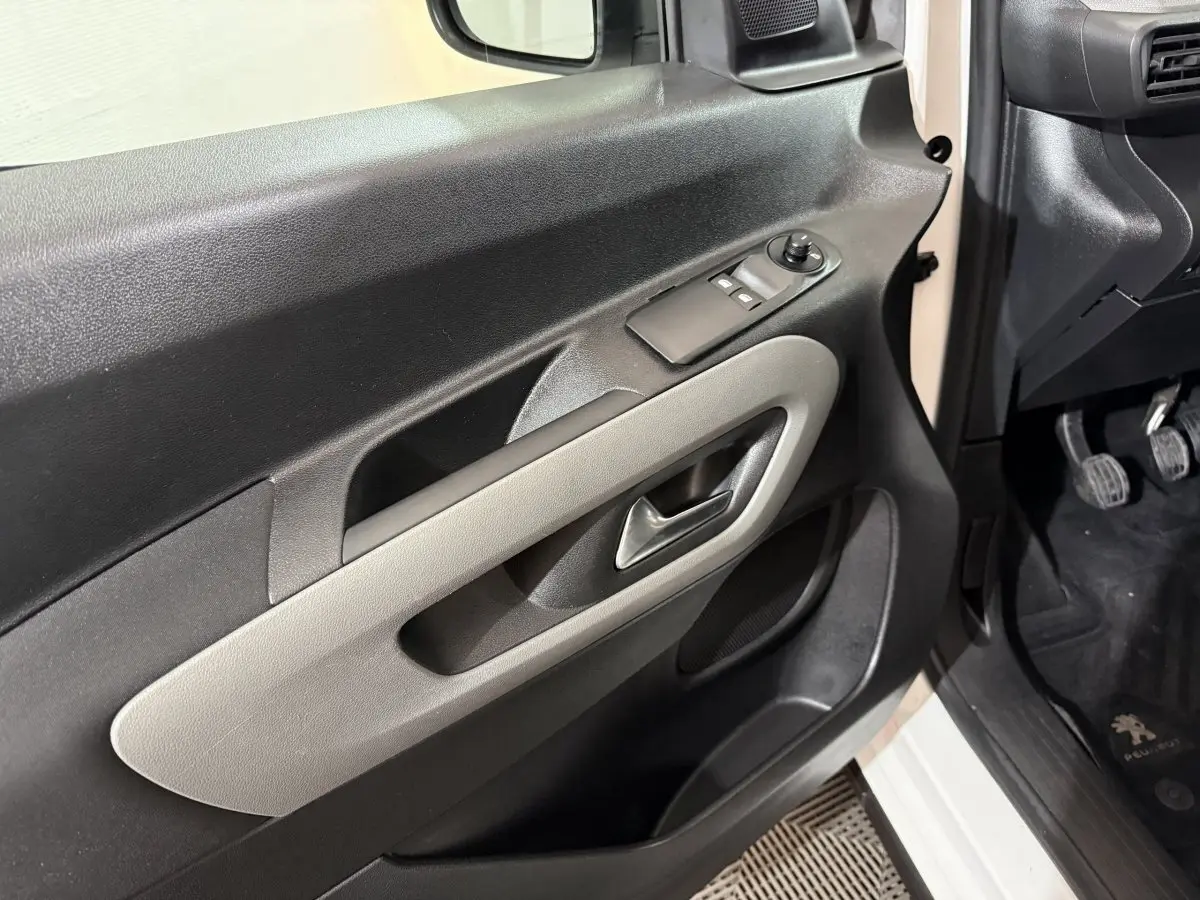 Vue rapprochée de la porte avant gauche noire et beige du Peugeot Rifter blanc, avec commandes de vitres et poignée intégrée.