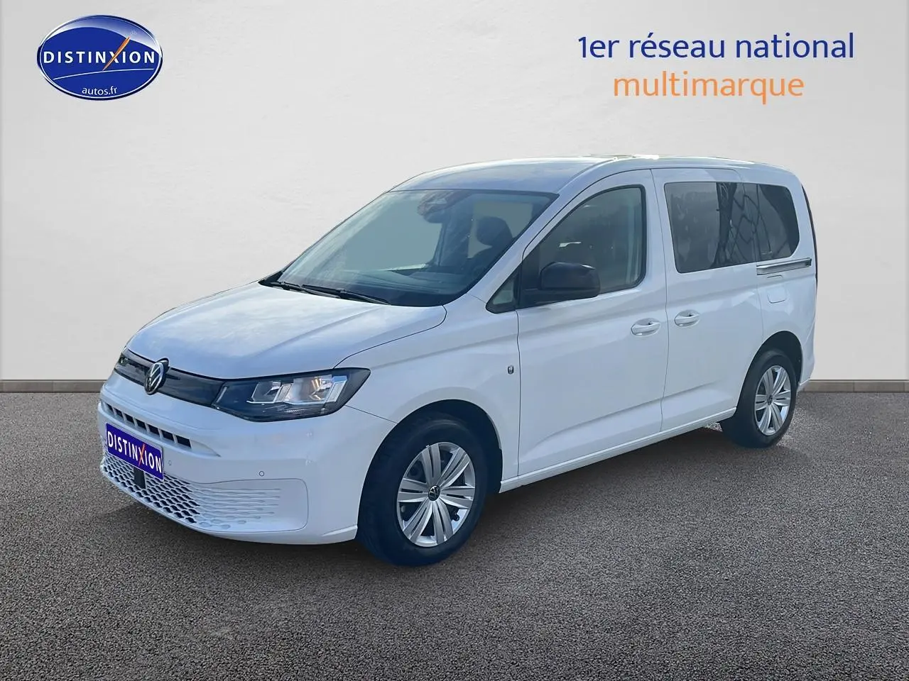 Volkswagen Caddy blanc vue 3/4 avant droit avec phares halogènes et jantes alliage simples.