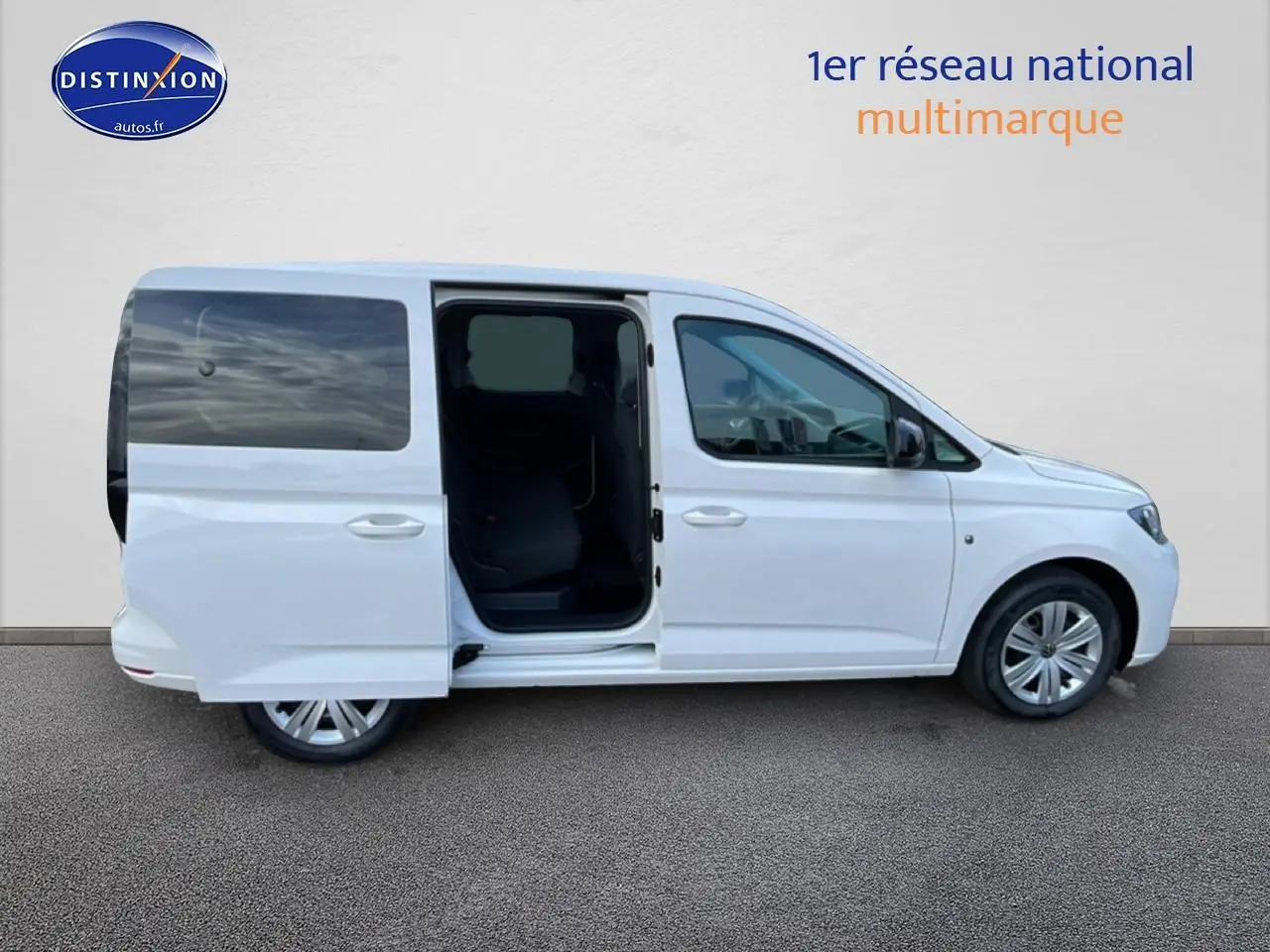 Vue de profil droit d'un Volkswagen Caddy blanc 2025 avec porte coulissante arrière ouverte sur fond neutre.