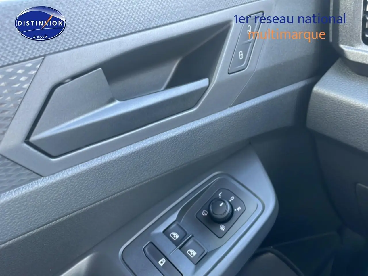 Gros plan sur la porte avant gauche du Volkswagen Caddy blanc, montrant les commandes des vitres et rétroviseurs.