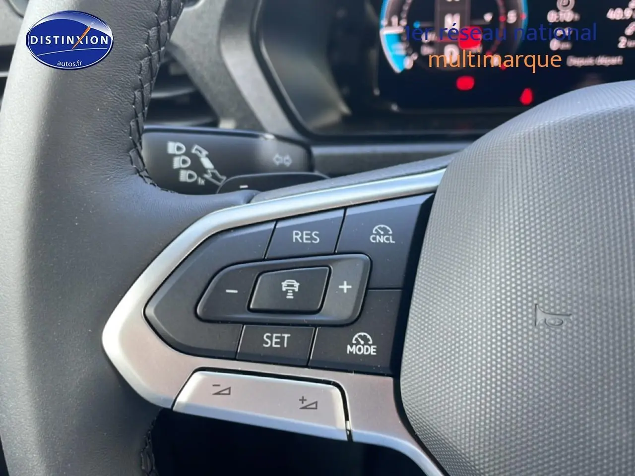 Gros plan sur le volant cuir multifonction du Volkswagen Caddy blanc, avec commandes de régulateur adaptatif visibles.