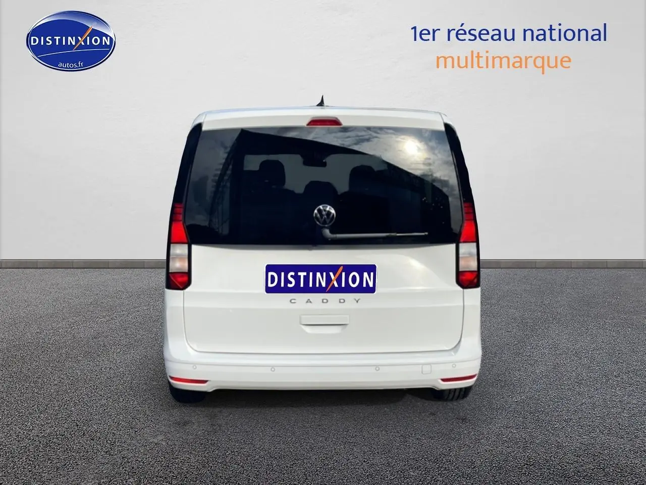 Vue arrière d'un Volkswagen Caddy blanc 2025 avec vitres arrière teintées et feux verticaux rouges.