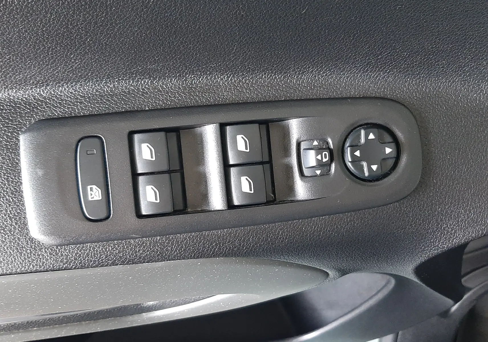 Gros plan sur les commandes de lève-vitres et réglage des rétroviseurs côté conducteur d'un Citroën Berlingo vert 2019.