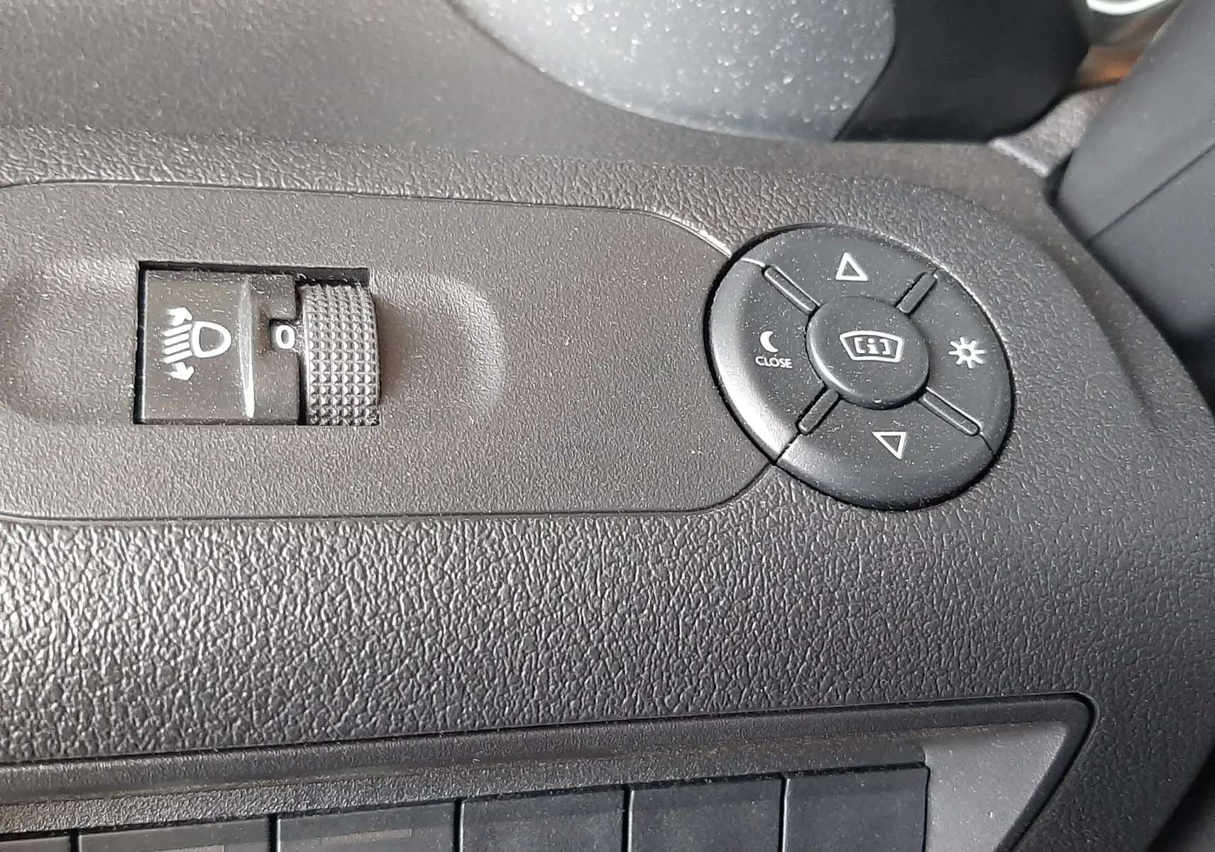 Détail du tableau de bord côté conducteur du Citroën Berlingo 2019, commandes de réglage des phares et des rétroviseurs.