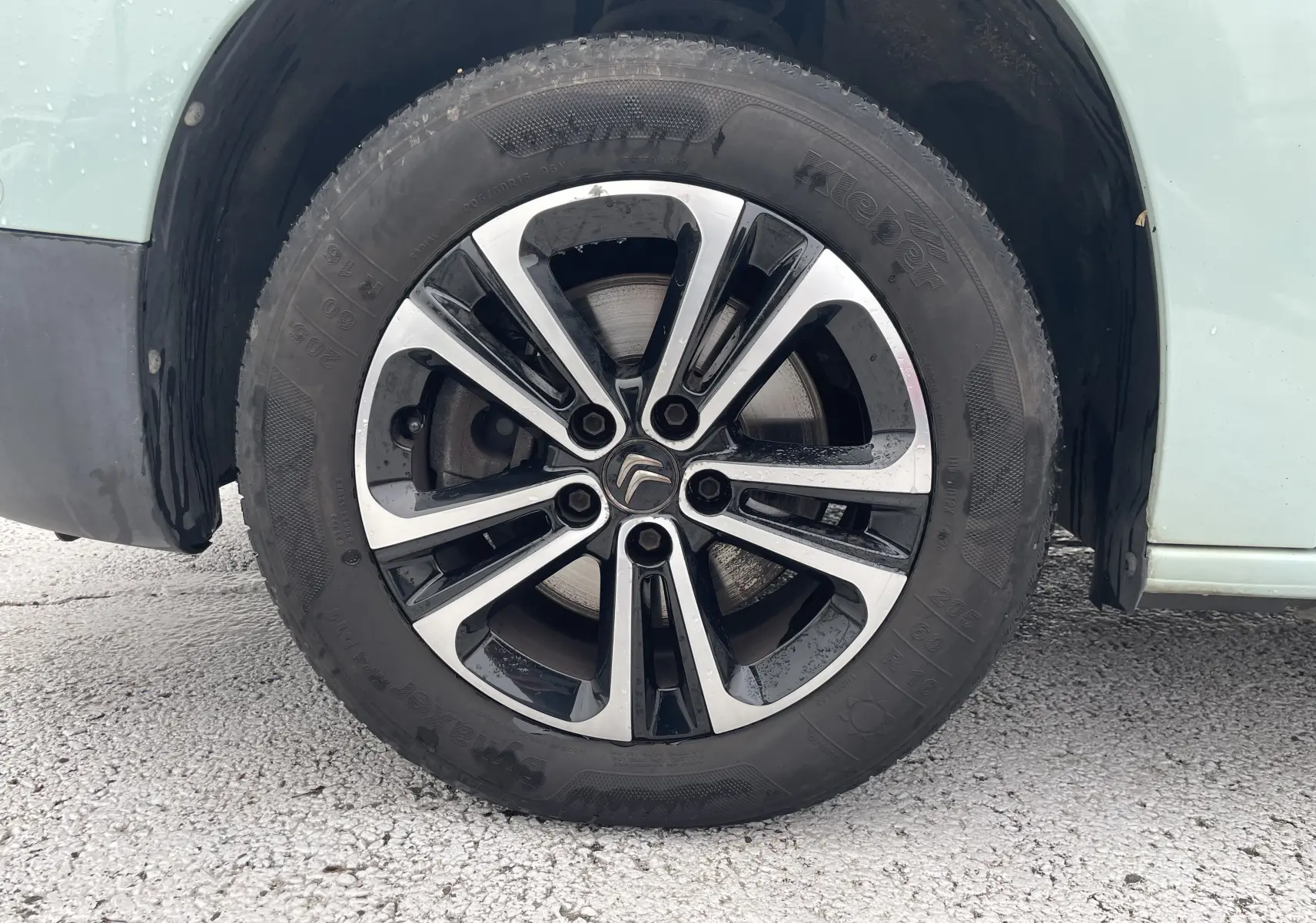 Gros plan sur la roue avant droite d’un Citroën Berlingo vert 2019, avec jante alliage bicolore et logo Citroën central.