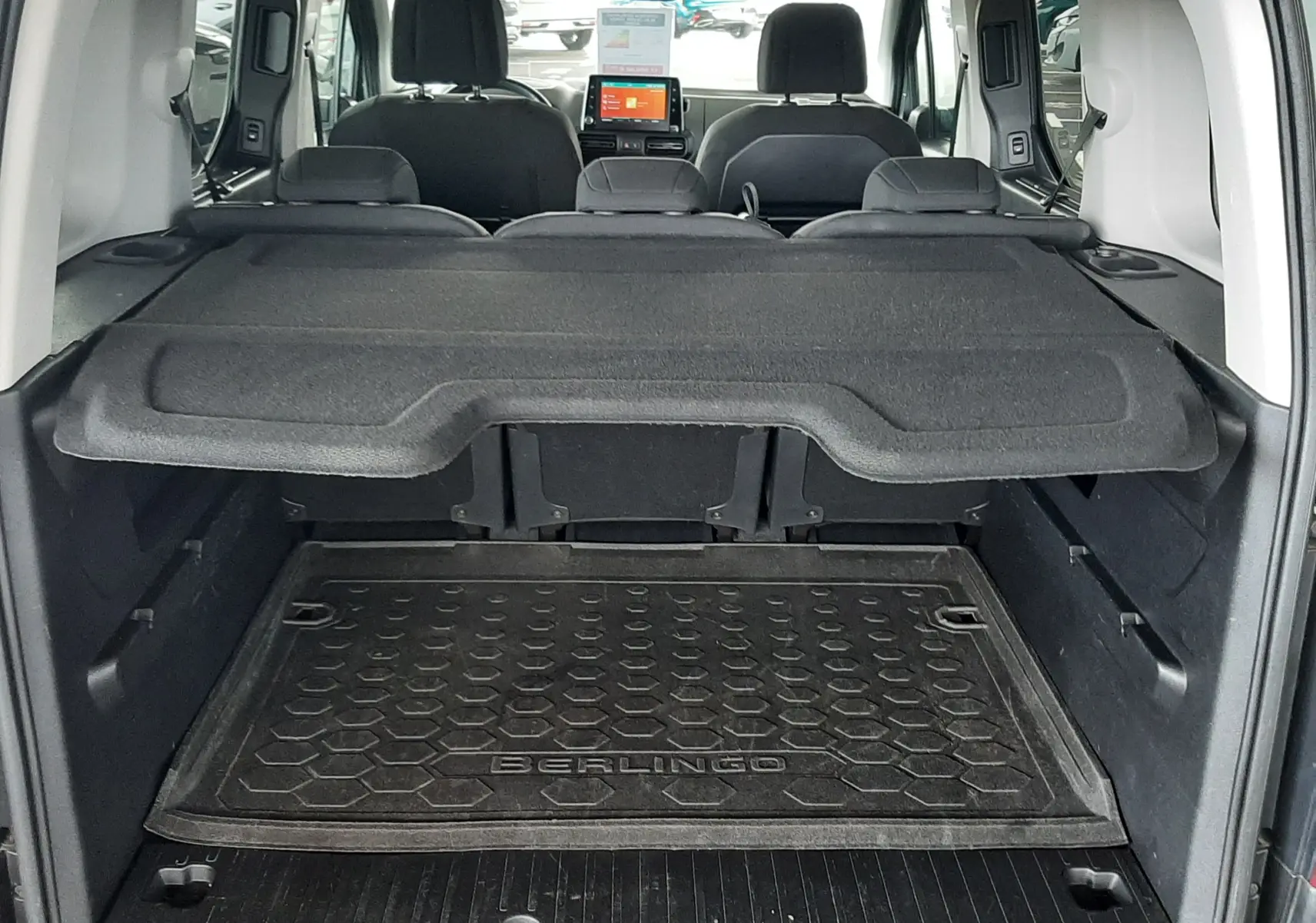 Vue arrière du coffre du Citroën Berlingo 2019 vert, avec tablette de séparation et tapis de sol marqué Berlingo.