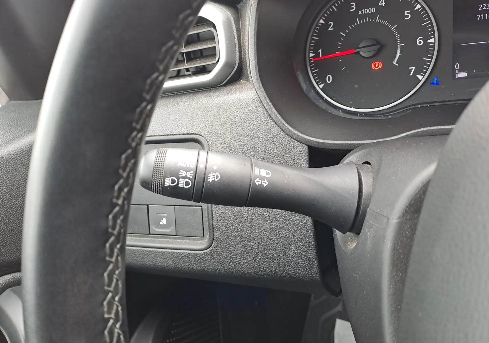 Gros plan sur la commande des phares et clignotants à gauche du volant noir du Dacia Duster 2024, tableau de bord visible.