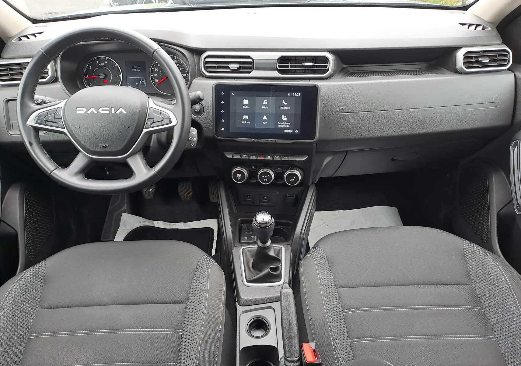 Vue intérieure avant du Dacia Duster 2024, tableau de bord noir avec écran tactile et volant multifonction.