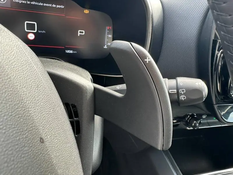 Gros plan sur la palette de changement de vitesse droite du Citroën C5 Aircross 2025 noir, avec tableau de bord numérique en arrière-plan.