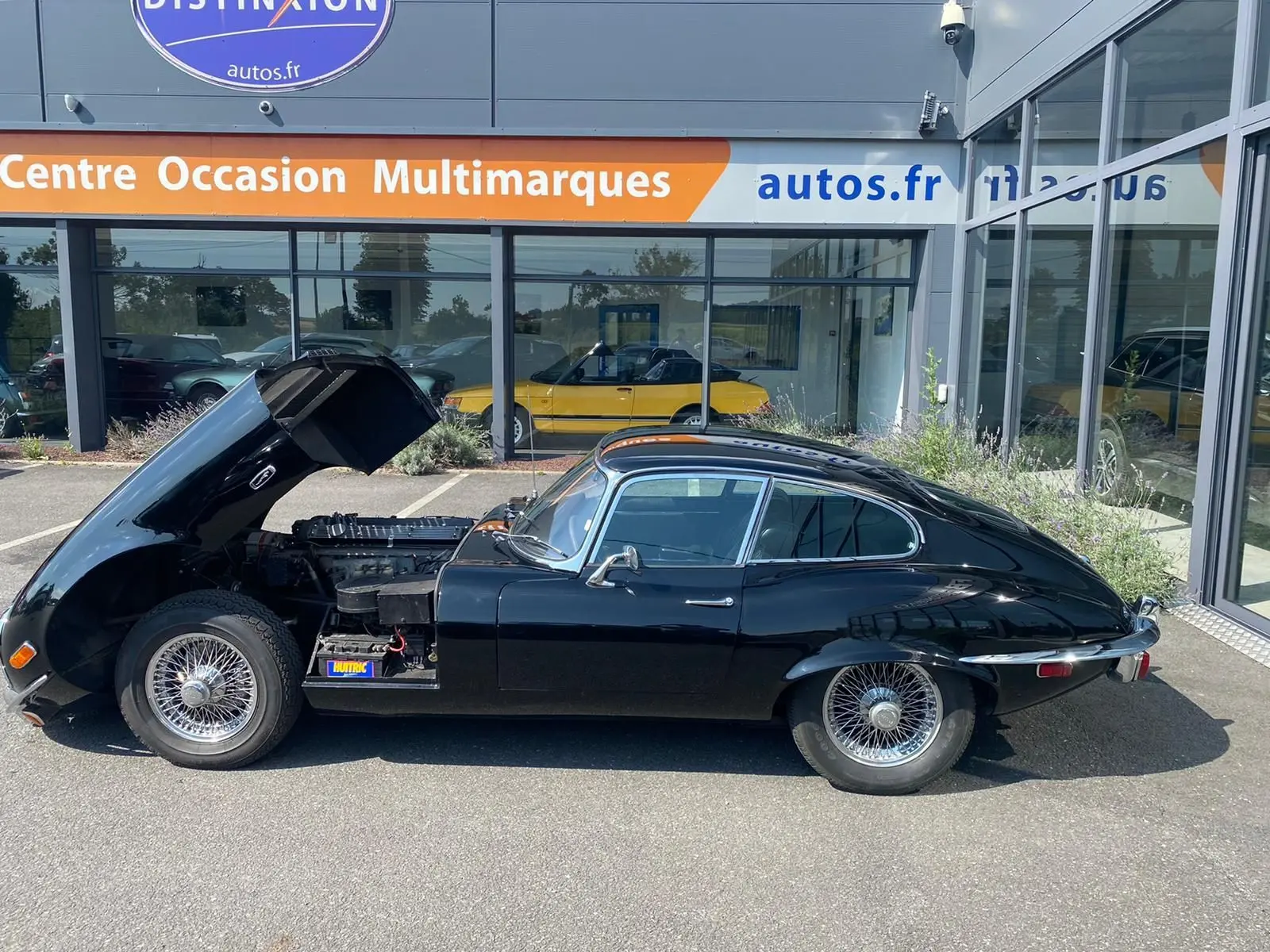 Profil côté gauche d'une Jaguar S-Type Type E Coupé 4.2 noire de 1970 avec capot avant ouvert dévoilant le moteur.