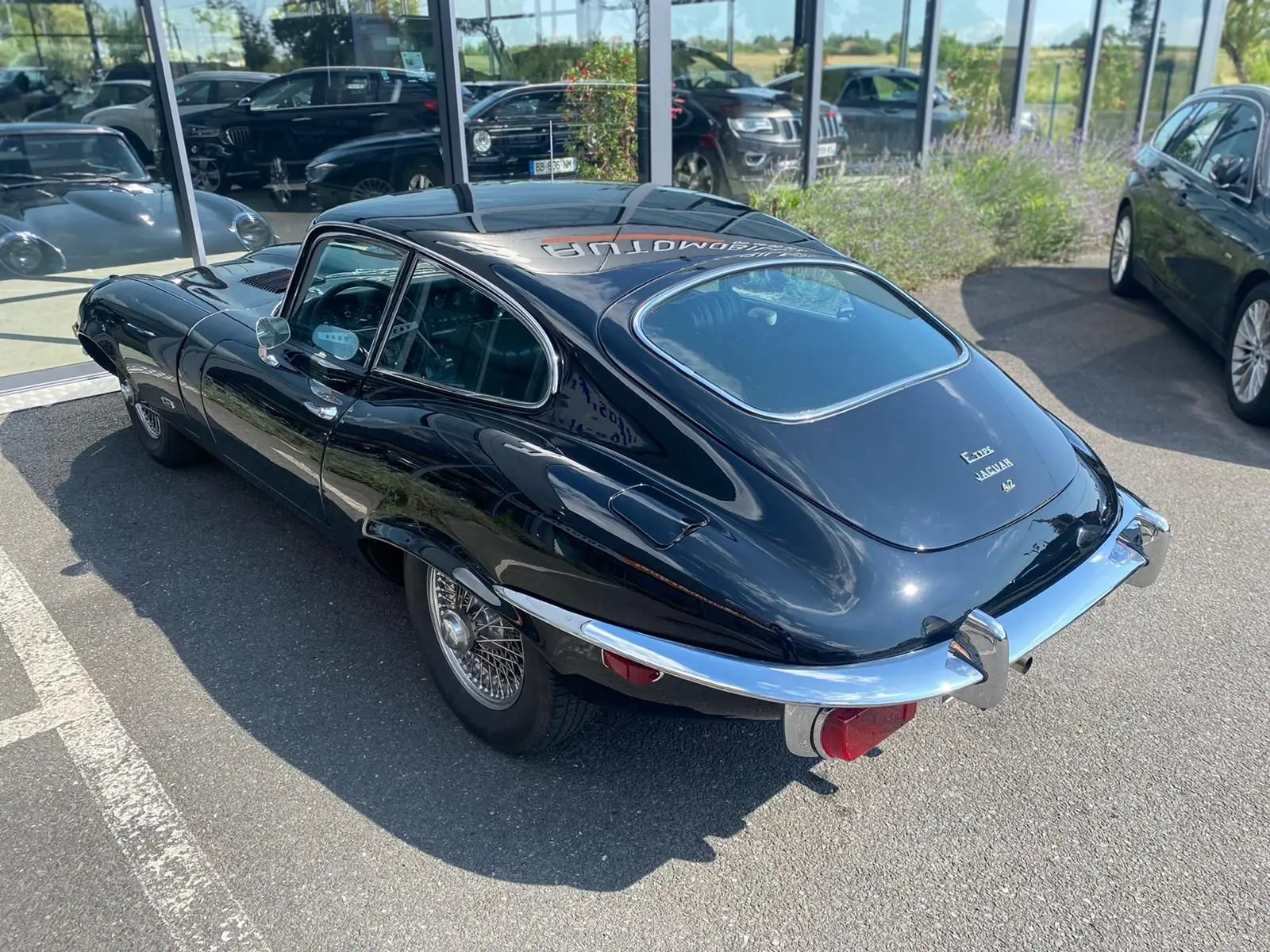 Vue 3/4 arrière droite d'une Jaguar S-Type noire de 1970 avec jantes à rayons et pare-chocs chromés distinctifs.