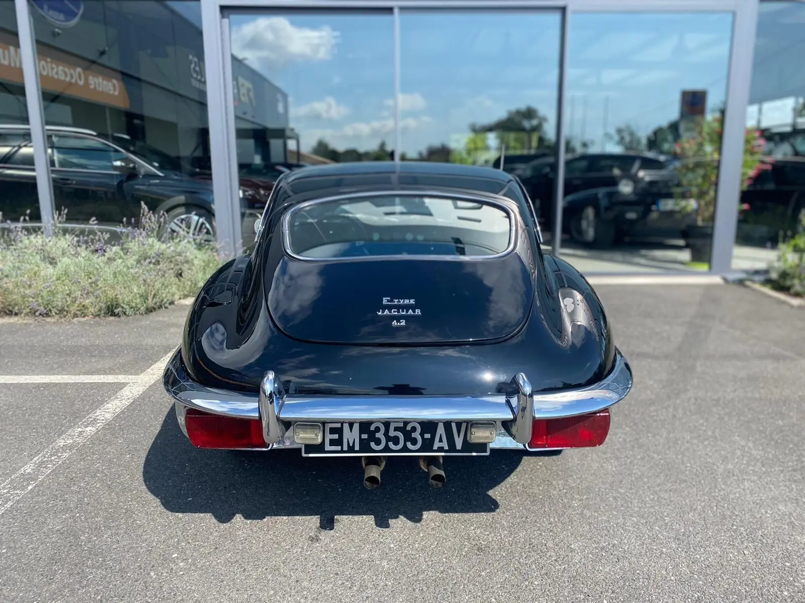 Vue arrière d'une Jaguar Type E Coupé 4.2 noire de 1970, avec ses doubles sorties d'échappement chromées visibles.