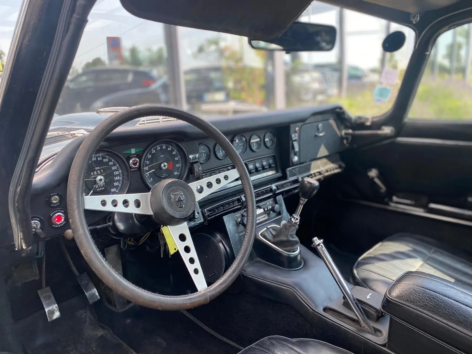 Intérieur noir vu côté conducteur d'une Jaguar S-Type Type E Coupé 4.2 Série 2 de 1970 avec volant trois branches et levier de vitesse manuel.