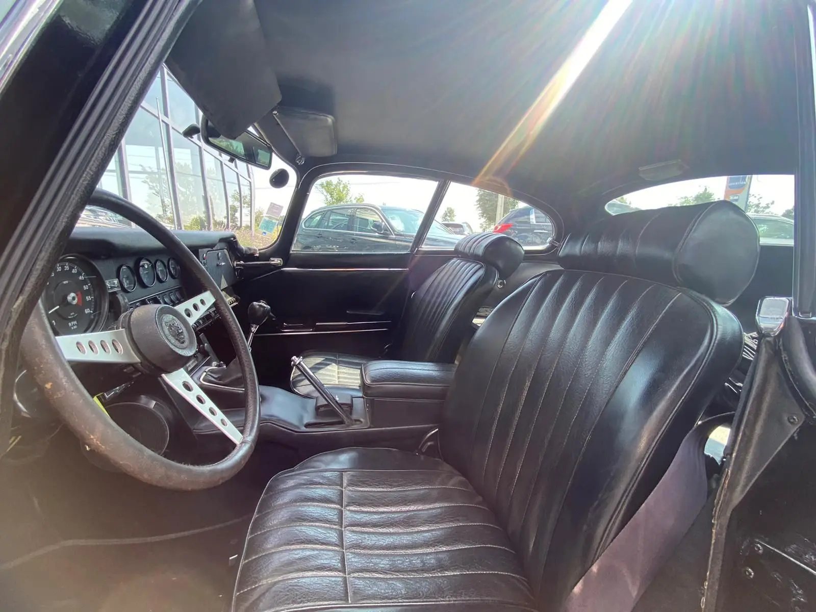 Intérieur noir du Jaguar S-Type Type E Coupé 4.2 Série 2 de 1970, vue côté conducteur montrant le volant et les sièges en cuir.