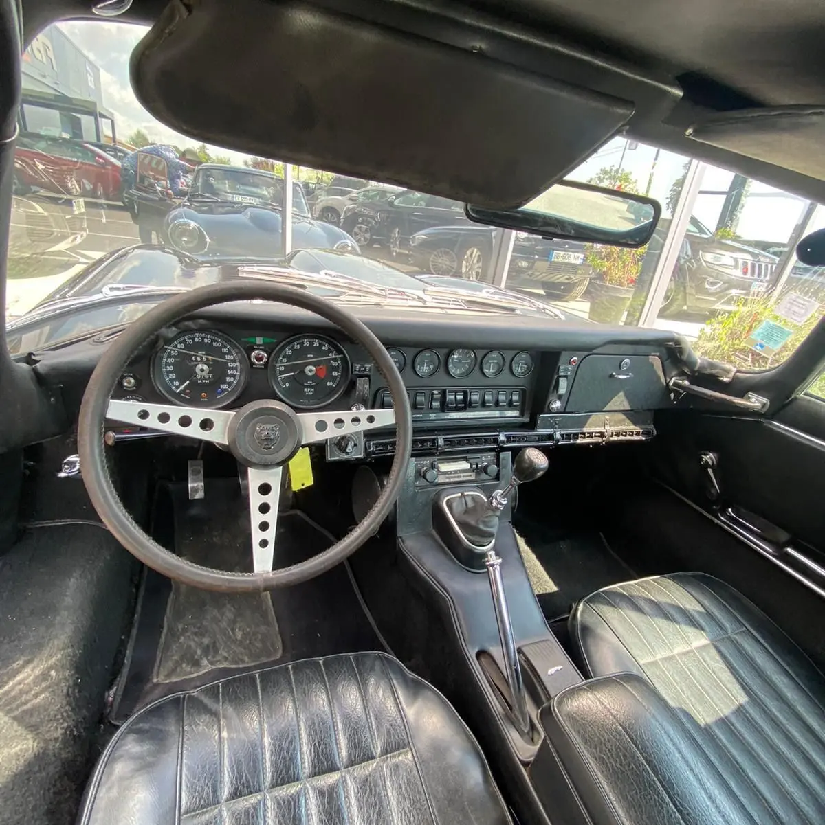 Intérieur noir de la Jaguar S-Type 1970, vue du poste de conduite avec tableau de bord vintage et volant trois branches.