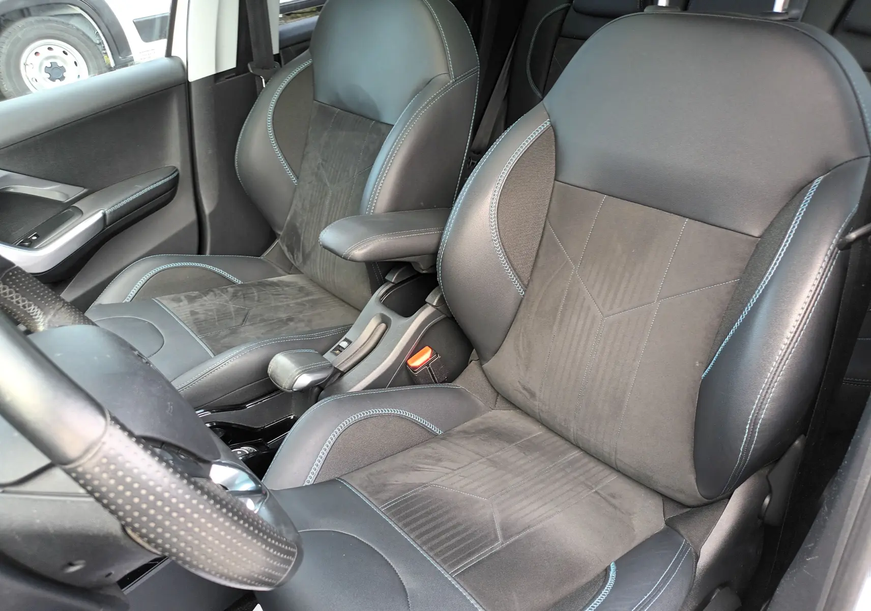 Vue intérieure côté conducteur du Peugeot 2008 blanc de 2018, mettant en valeur les sièges sport noirs avec surpiqûres bleues.