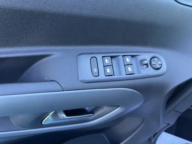 Commande des vitres électriques et poignée de porte côté gauche dans l'habitacle noir du Citroën Berlingo N1 2025.