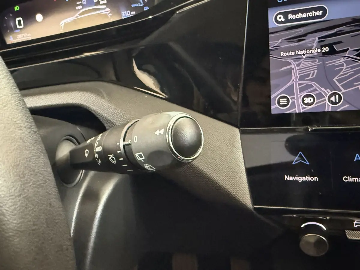 Gros plan sur la commande d’essuie-glace et partie du tableau de bord noir avec écran tactile affichant la navigation dans une Peugeot 308 bleu.