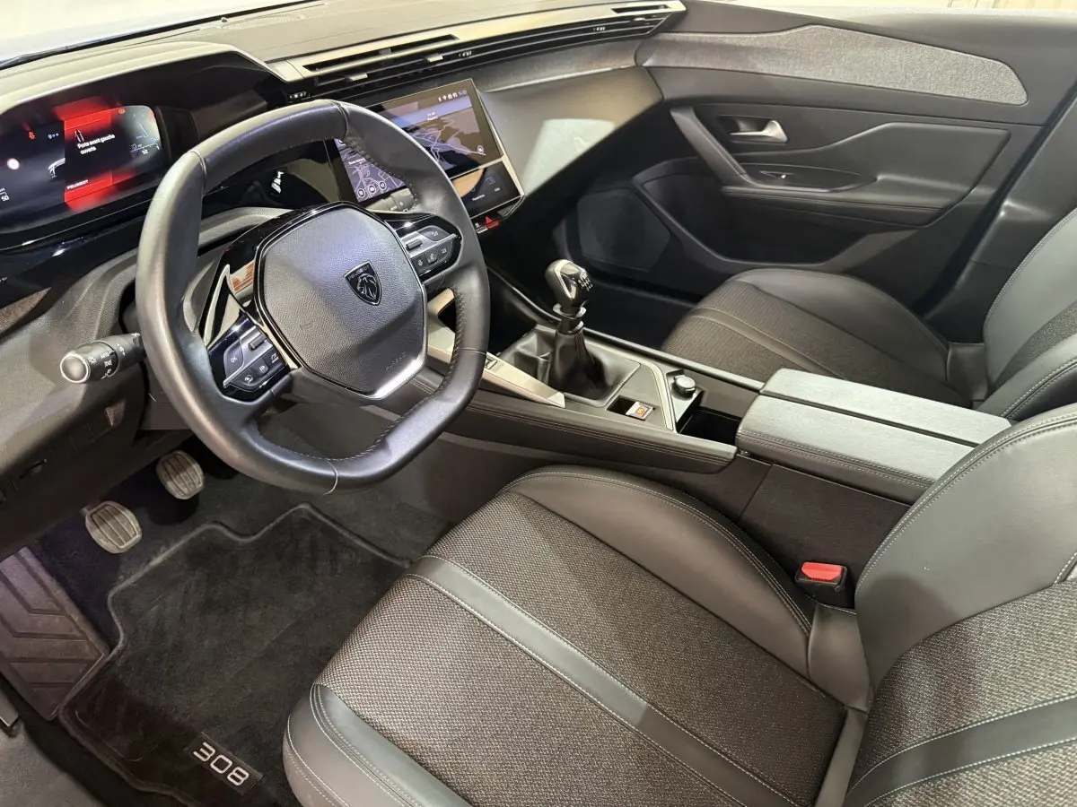 Intérieur de la Peugeot 308 2023, vue côté conducteur, volant cuir, boîte manuelle et écran tactile central.