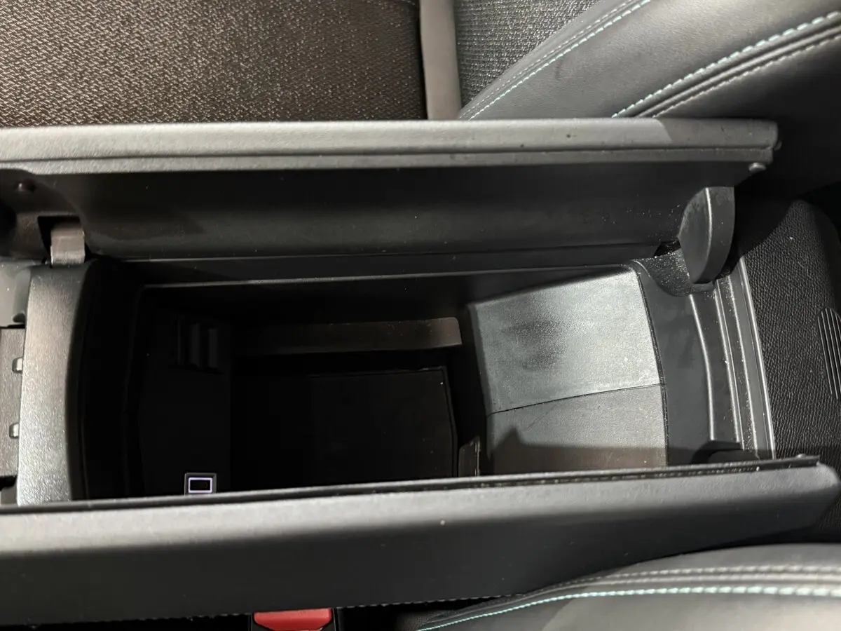 Vue plongeante sur le rangement central ouvert de la Peugeot 308 bleu, intérieur noir avec surpiqûres bleues.