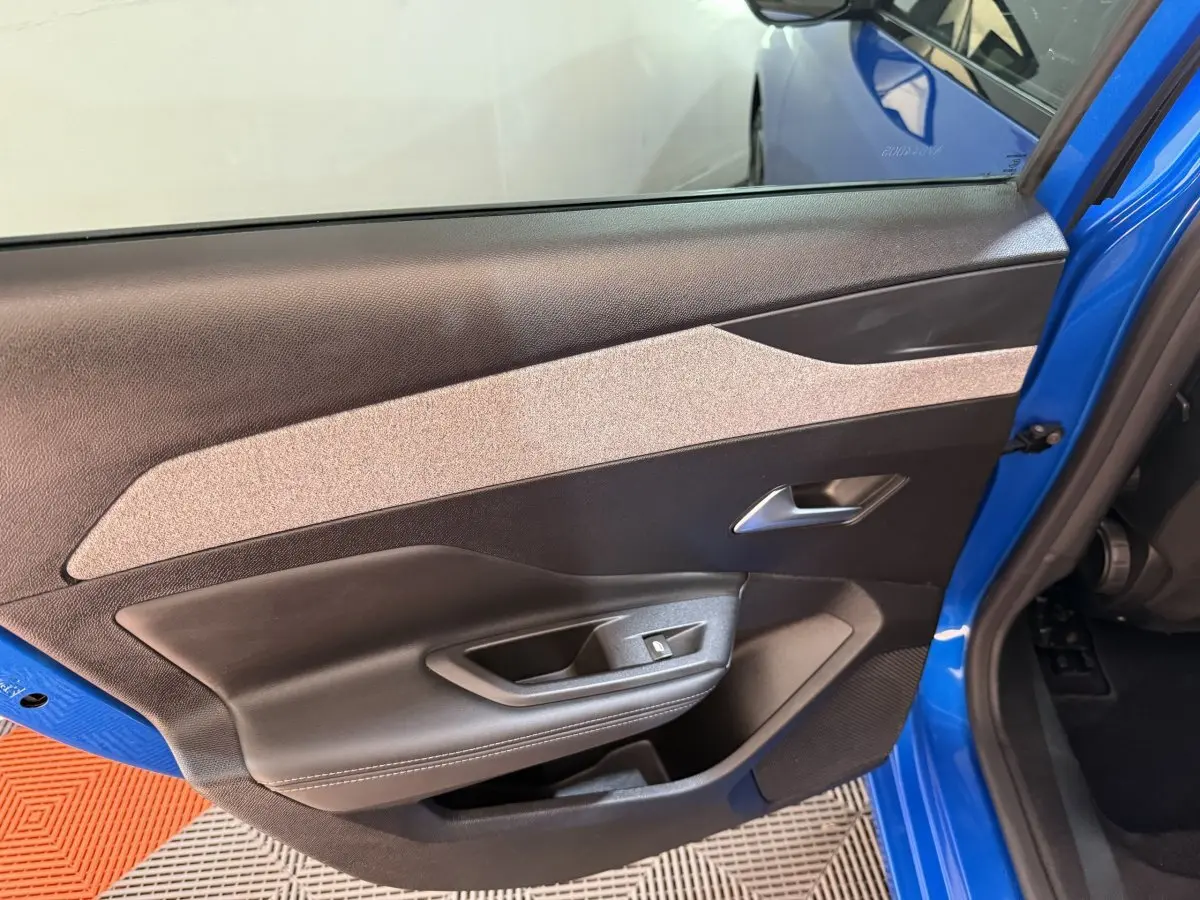 Vue rapprochée de la porte avant gauche bleu vif de la Peugeot 308 2023, avec garniture intérieure noire et beige.