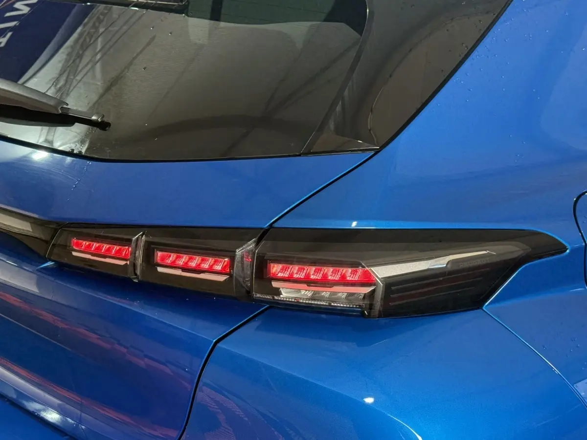Gros plan sur le feu arrière droit rouge et noir d'une Peugeot 308 bleu 2023, soulignant la ligne moderne du hayon.