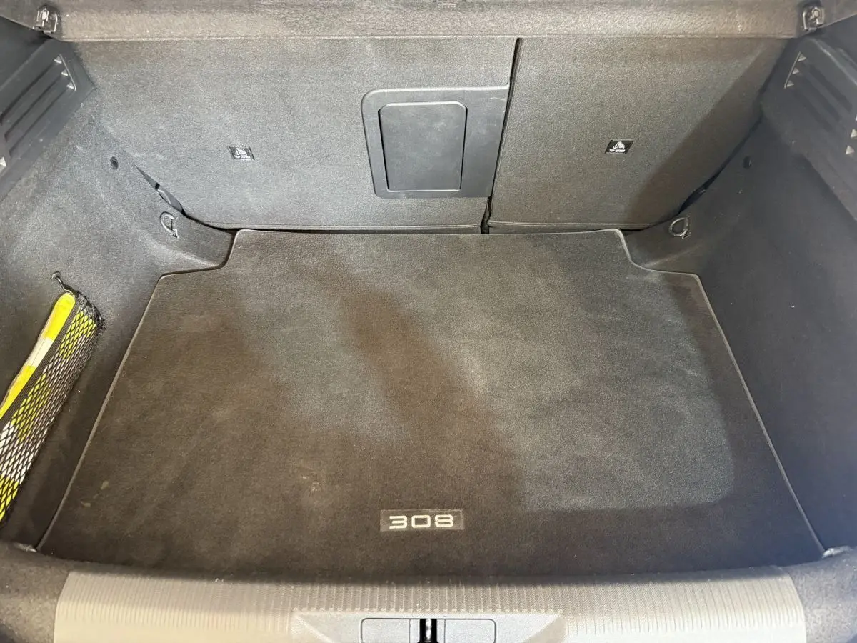 Coffre spacieux vu de dessus, tapis noir avec logo 308, intérieur de Peugeot 308 PureTech 2023.