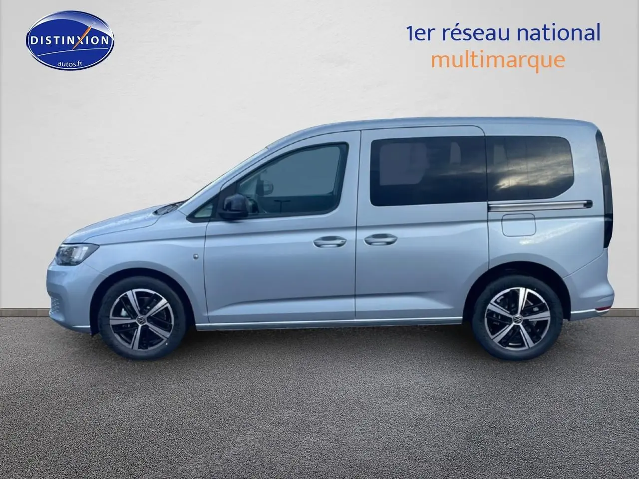 Vue de profil côté gauche d'un Volkswagen Caddy gris argent 2025 avec vitres arrière teintées et jantes alliage.