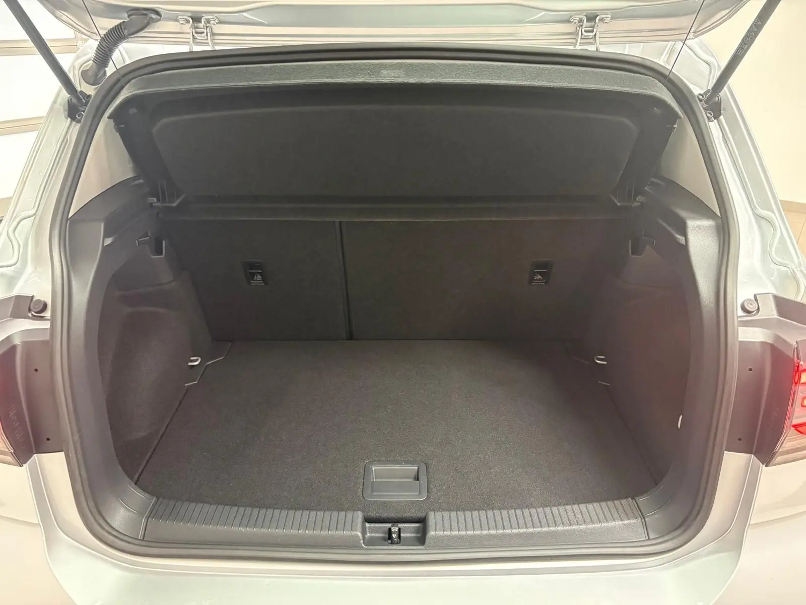 Coffre ouvert vu de l'arrière d'un Volkswagen T-Cross 2024 reflet d'argent, intérieur noir et espace de chargement vide.