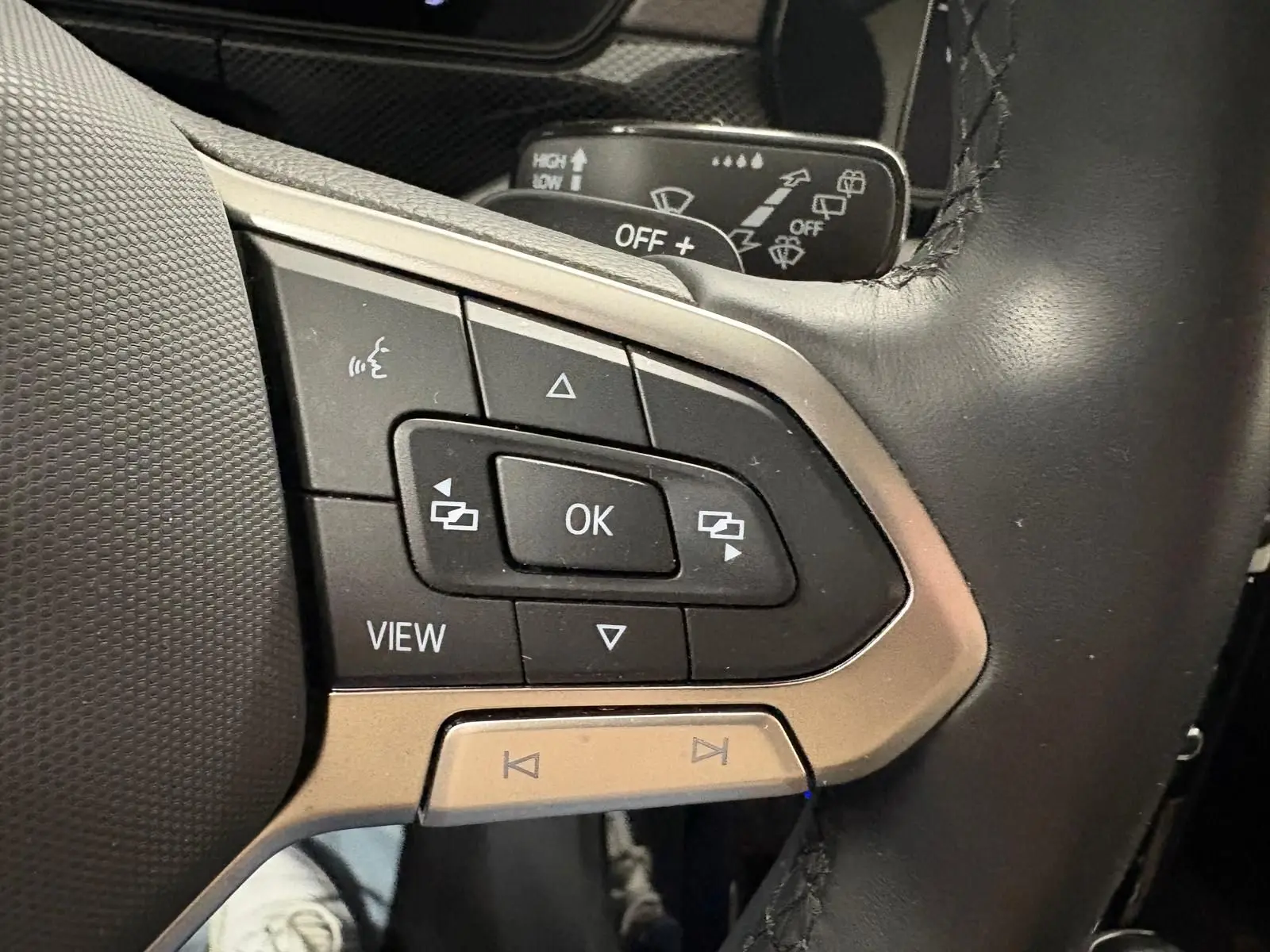 Gros plan sur les commandes multifonctions noires et argent du volant cuir du Volkswagen T-Cross 2024.