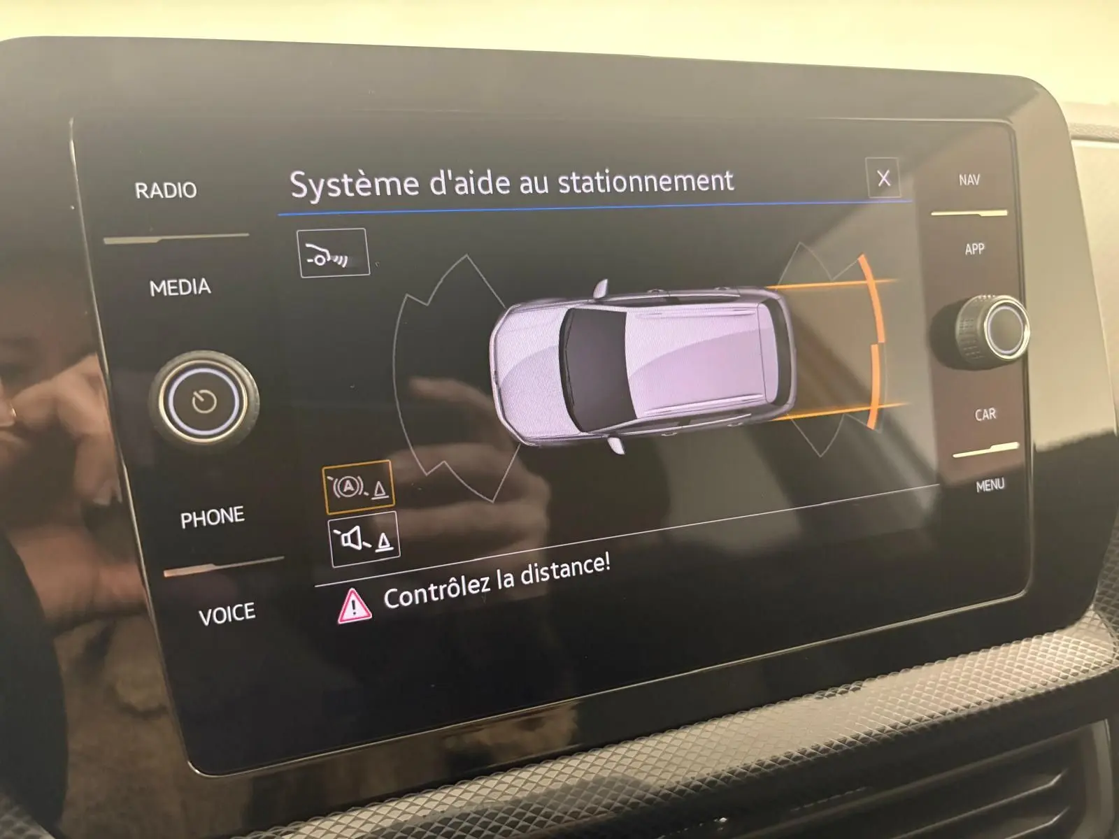 Écran tactile intérieur montrant le système d'aide au stationnement du Volkswagen T-Cross 2024 en vue de dessus du véhicule.