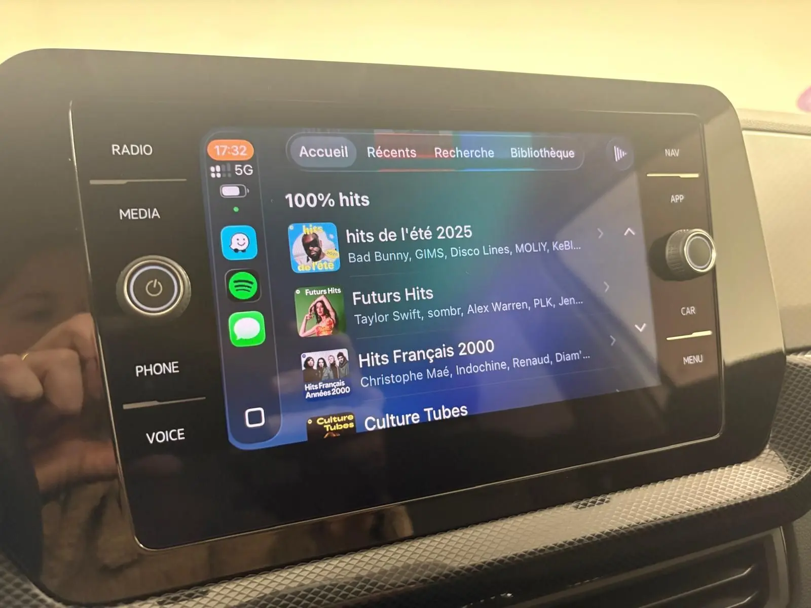 Écran tactile central du Volkswagen T-Cross 2024 en reflet d'argent, affichant l'interface multimédia avec playlists musicales.