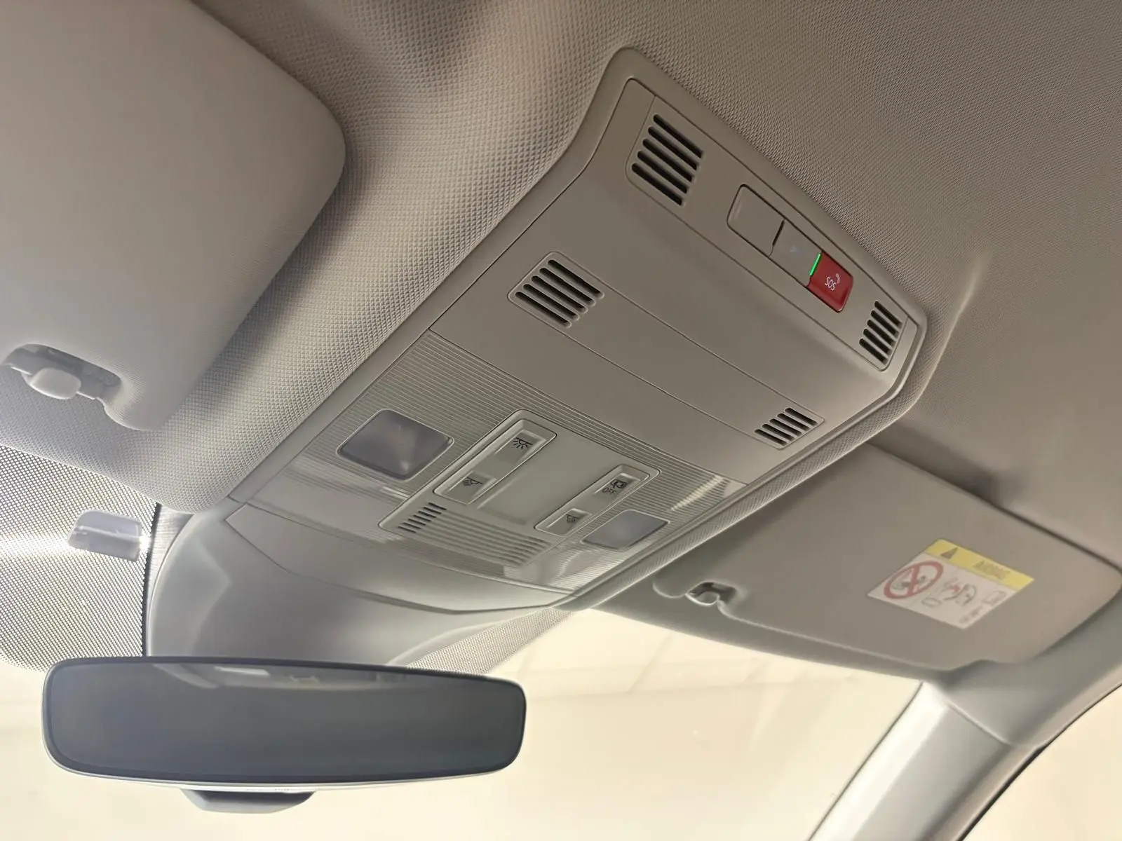 Vue intérieure du plafonnier gris clair avec commandes et rétroviseur dans un Volkswagen T-Cross 2024 reflet d'argent.