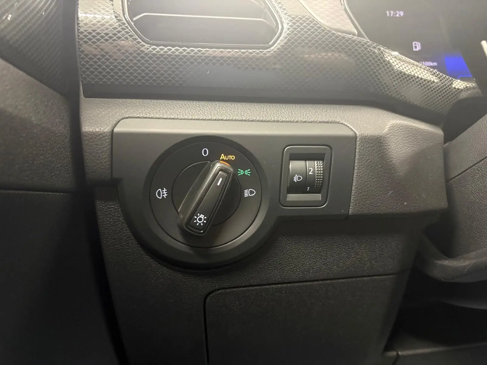 Gros plan sur le bouton de commande des phares et réglage d'intensité dans l'habitacle noir du Volkswagen T-Cross 2024.