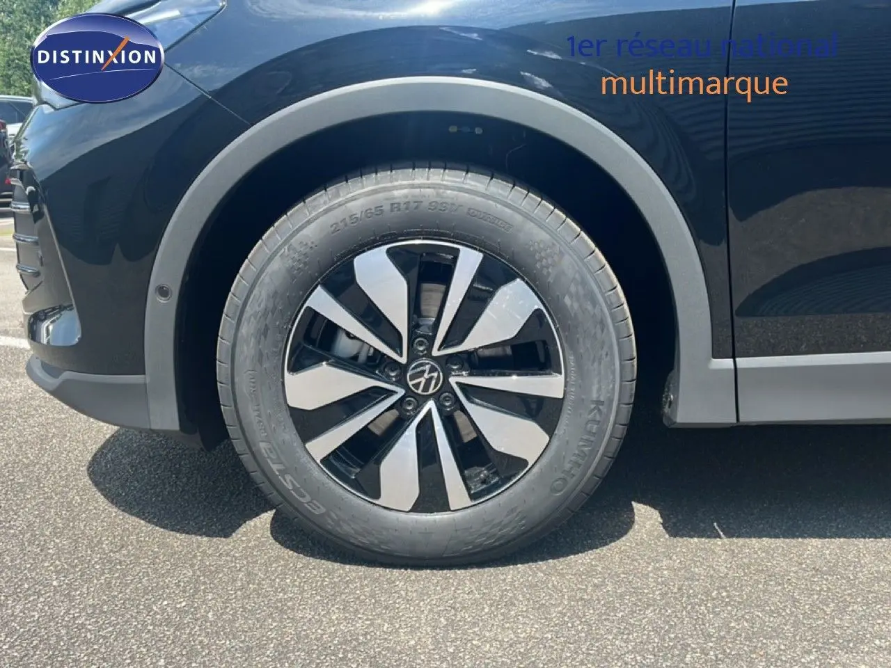 Gros plan sur la roue avant gauche du Volkswagen Tiguan noir Grenadilla métal, mettant en valeur la jante design et le pneu.
