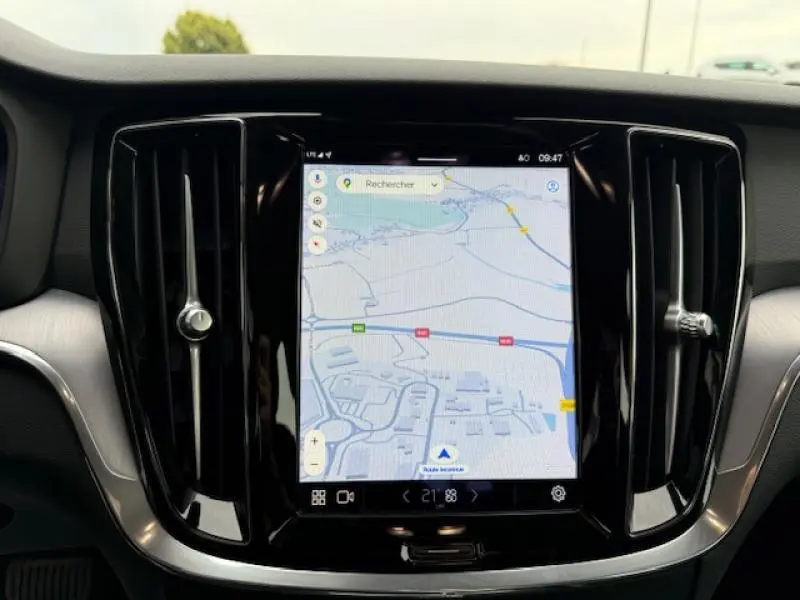 Écran tactile central du tableau de bord de la Volvo S60 2024 affichant la navigation GPS avec aérateurs verticaux noirs de chaque côté.