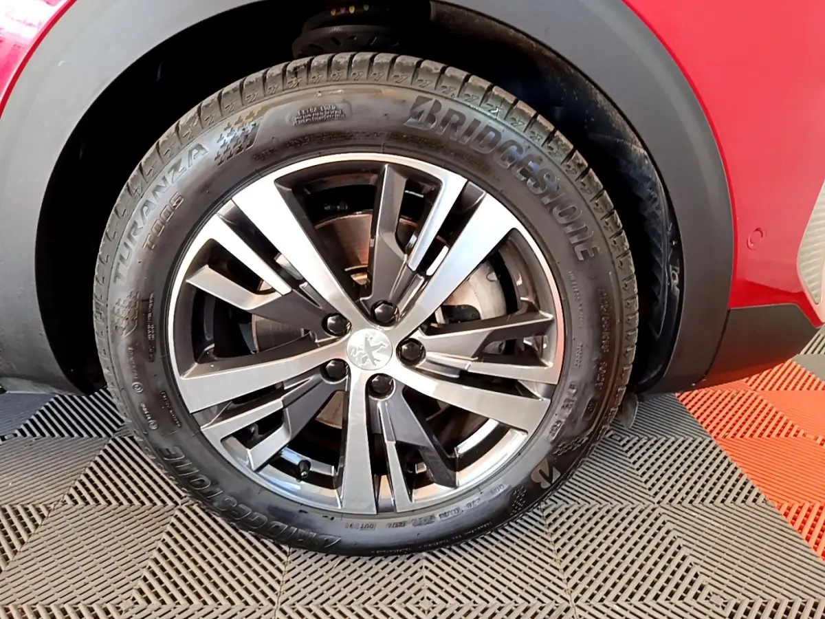 Gros plan sur l'arrière droit rouge du Peugeot 3008 1.6 Hybrid 225, avec passage de roue noir et jante visible.