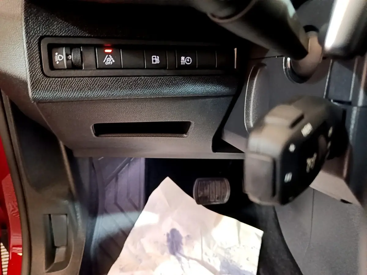 Détail intérieur côté gauche du Peugeot 3008 hybride 2021, montrant commandes et pédale avec partie de la carrosserie rouge.