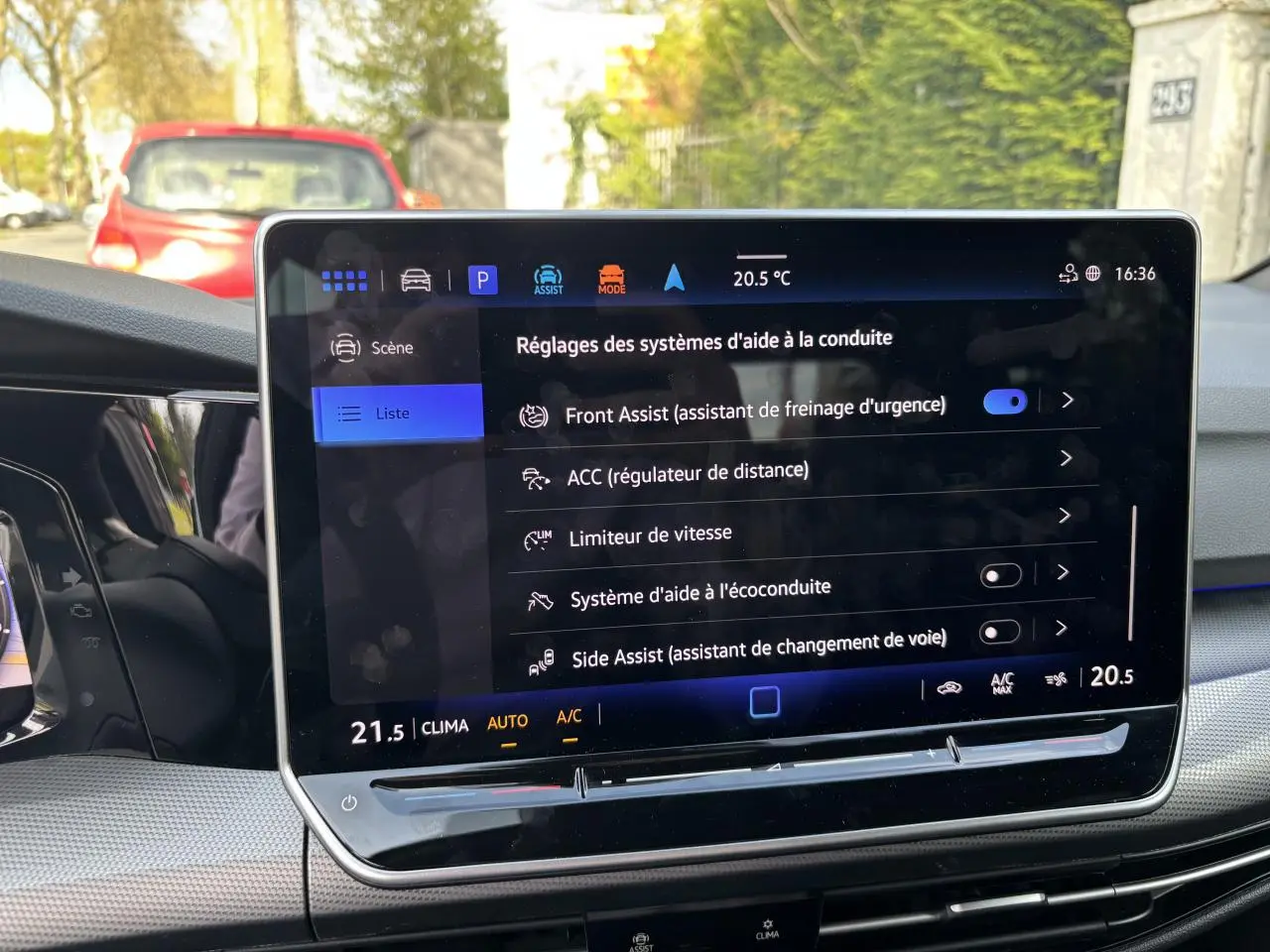 Vue intérieure du tableau de bord de la Volkswagen Golf blanche 2024, écran tactile affichant les aides à la conduite.