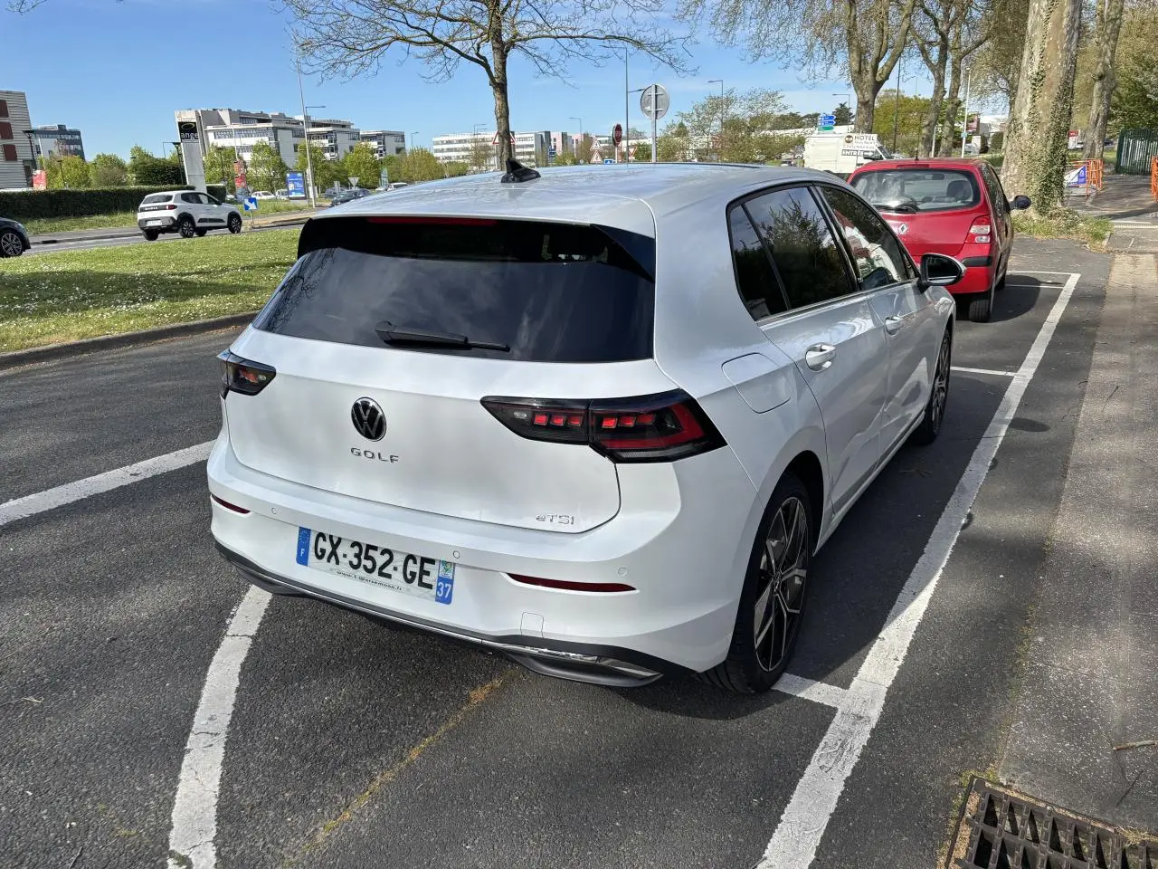 Vue 3/4 arrière droite d'une Volkswagen Golf blanche 2024, avec feux arrière LED et vitres teintées, stationnée sur rue.