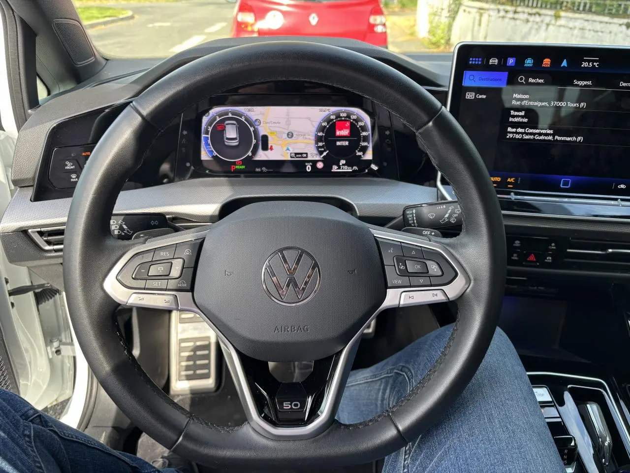 Vue intérieure centrée sur le volant noir de la Volkswagen Golf 1.5 eTSI Edition 50 avec tableau de bord numérique et écran tactile.