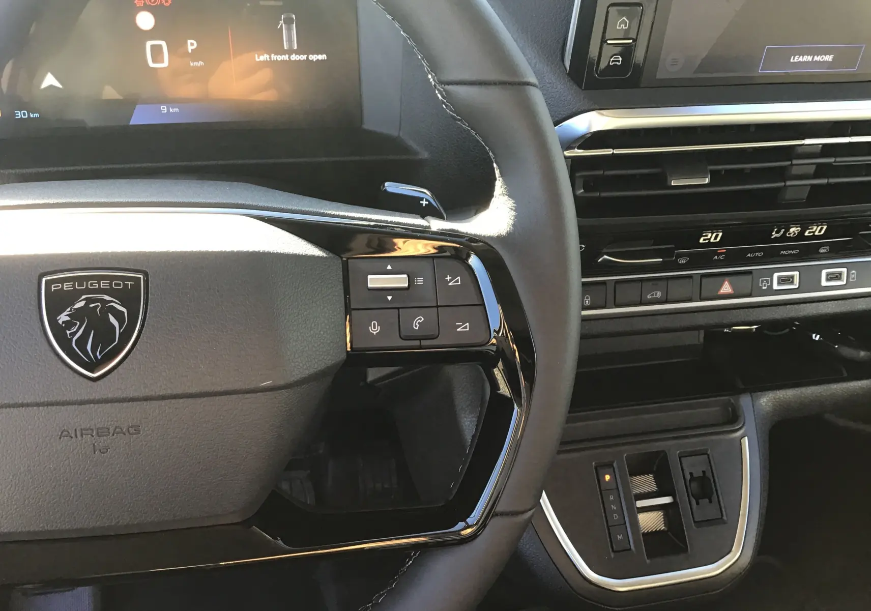 Vue rapprochée du volant noir et du tableau de bord numérique du Peugeot Expert Fourgon blanc 2024 avec commandes intégrées.