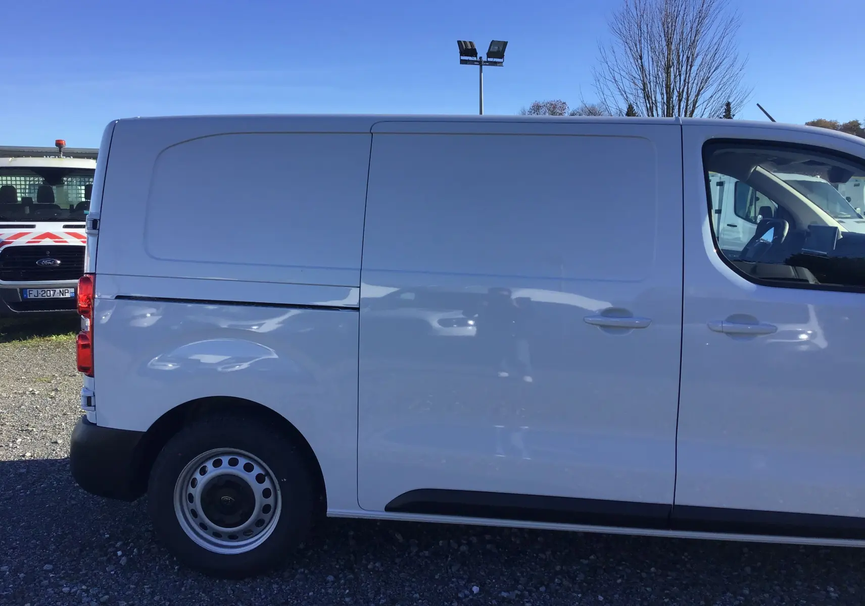 Profil côté gauche d'un Peugeot Expert Fourgon blanc 2024, mettant en valeur sa carrosserie lisse et ses roues acier.