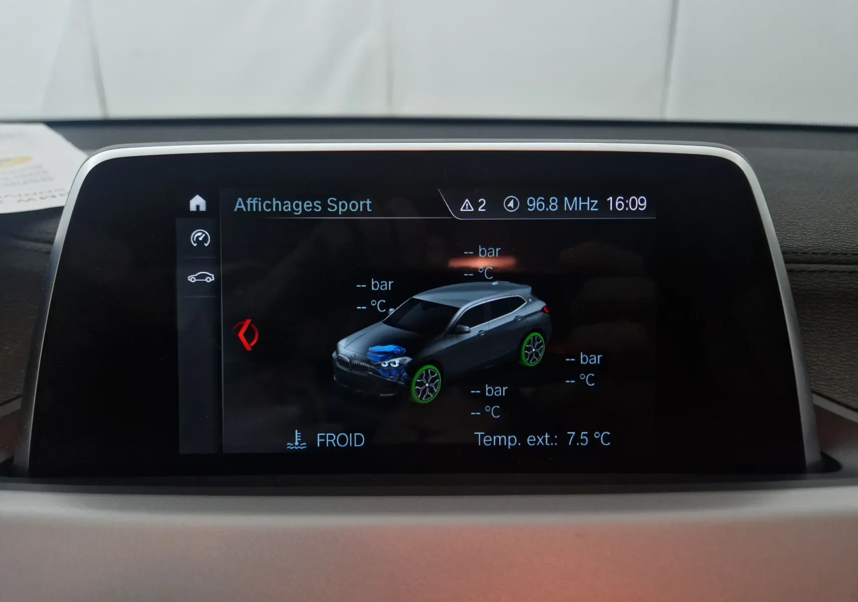 Écran multimédia montrant une vue 3D d’un BMW X2 gris clair métal en affichage sport, intérieur du véhicule.