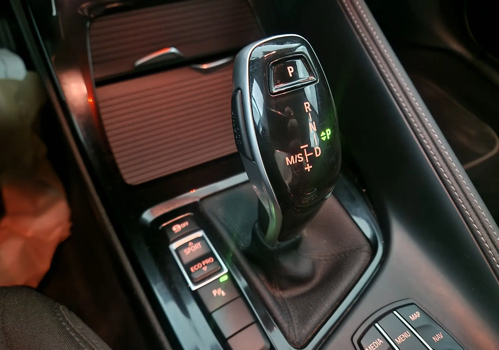 Gros plan sur le levier de vitesses automatique noir et les commandes de mode de conduite dans l’habitacle d’une BMW X2 gris clair.