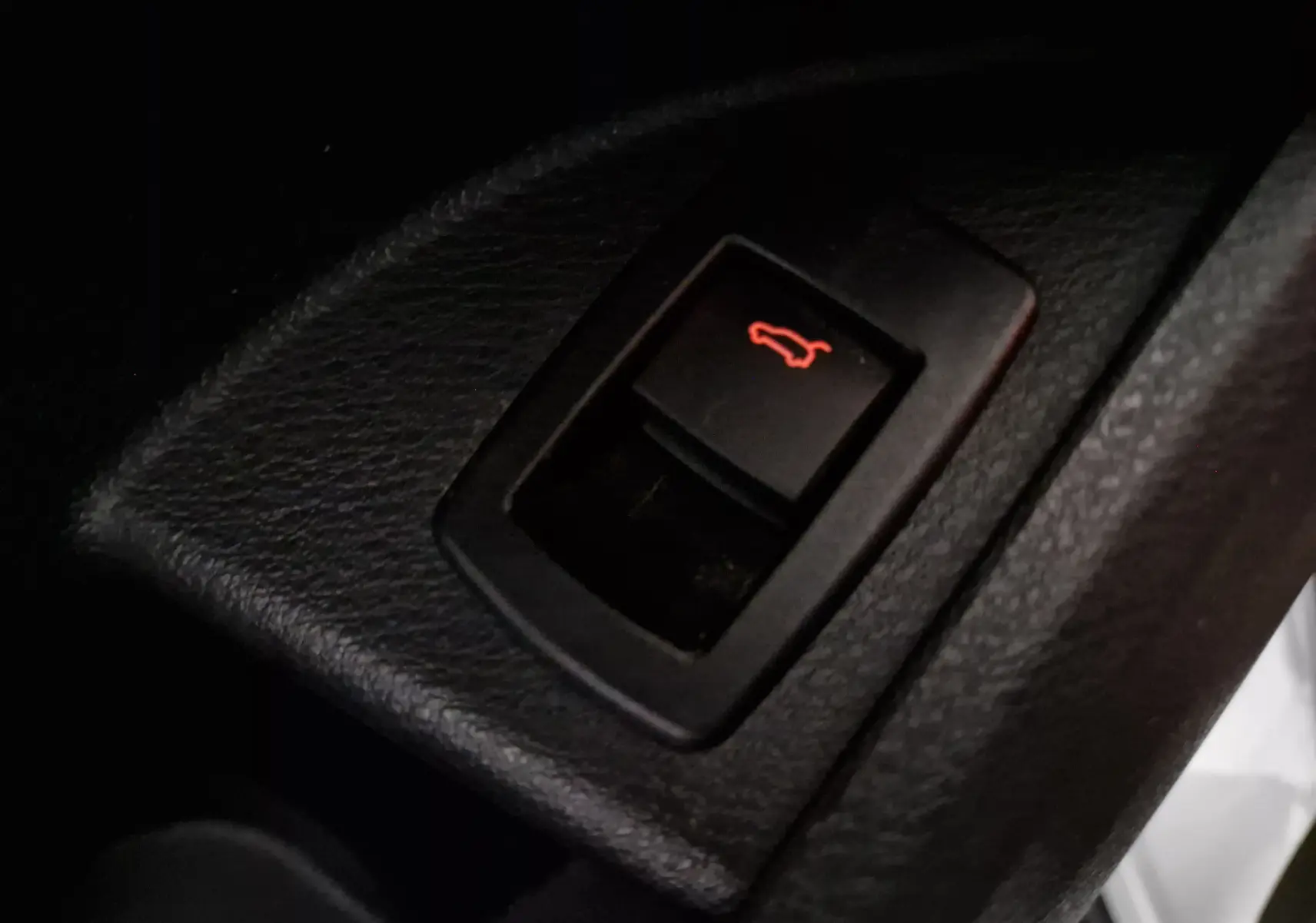 Gros plan sur le bouton d'ouverture du coffre intérieur d'une BMW X2 gris clair métal, version 2018.