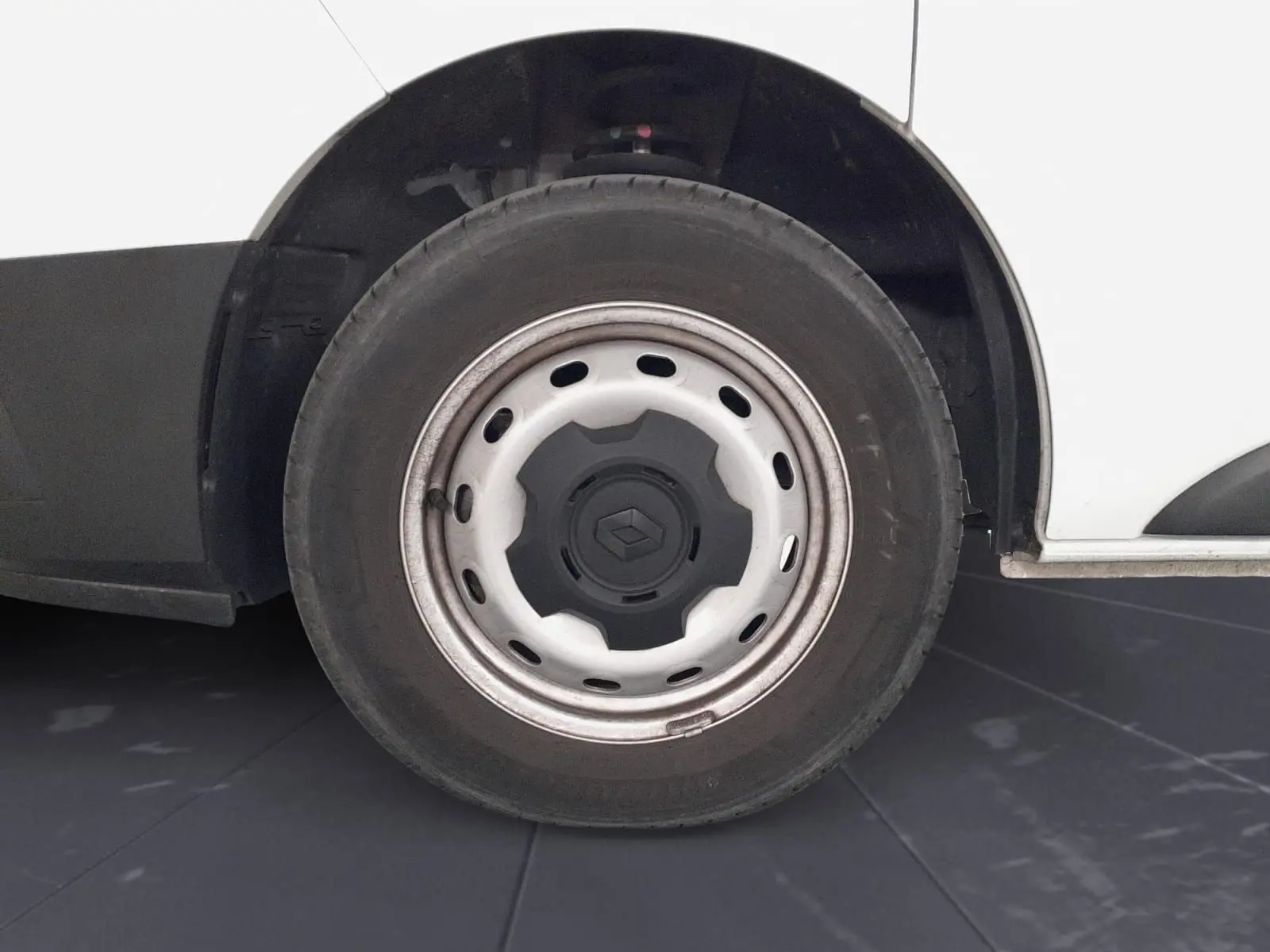 Gros plan sur la roue avant droite blanche d’un Renault Trafic Fourgon avec jante tôlée et logo central noir.