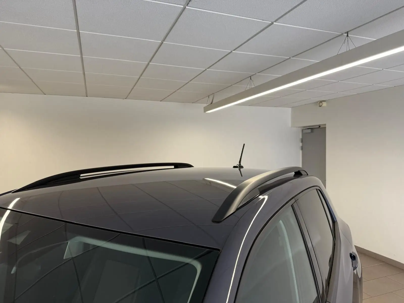 Vue en plongée du toit noir brillant et des barres de toit sur le côté droit du Volkswagen T-Cross gris cendre 2025.