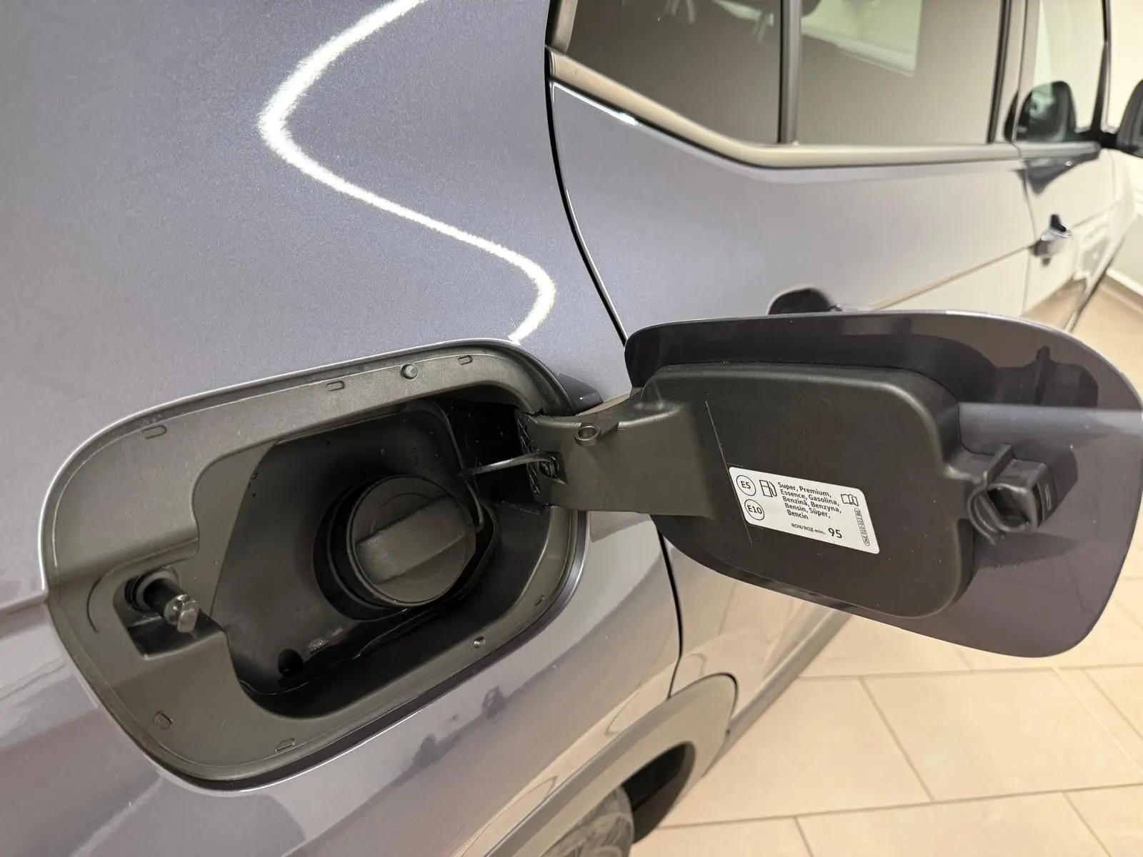 Vue rapprochée de la trappe à carburant ouverte côté gauche du Volkswagen T-Cross gris cendre 2025.